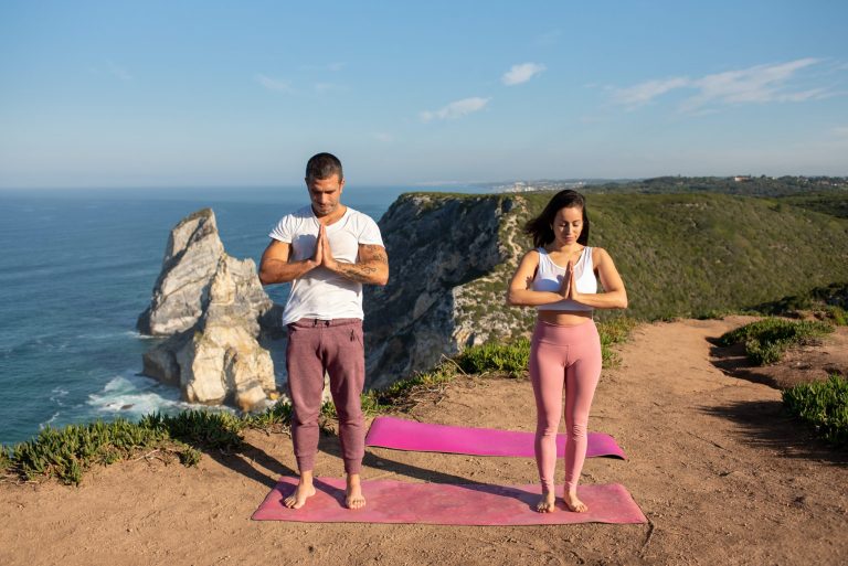 A men and a women practicing standing meditation on the beach