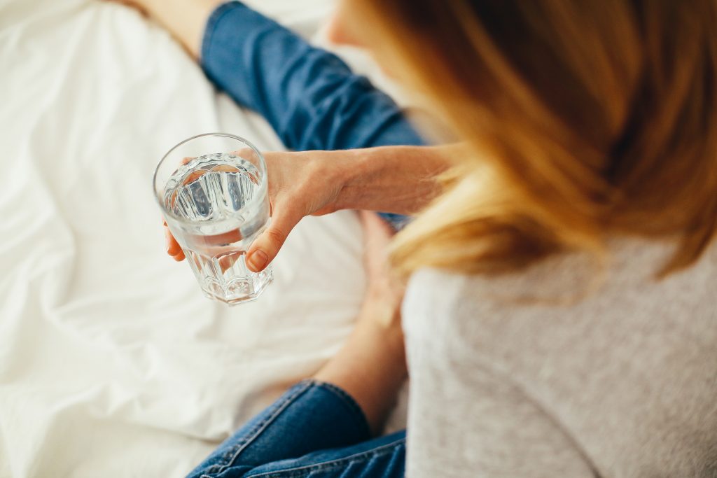 woman drink water on a bed