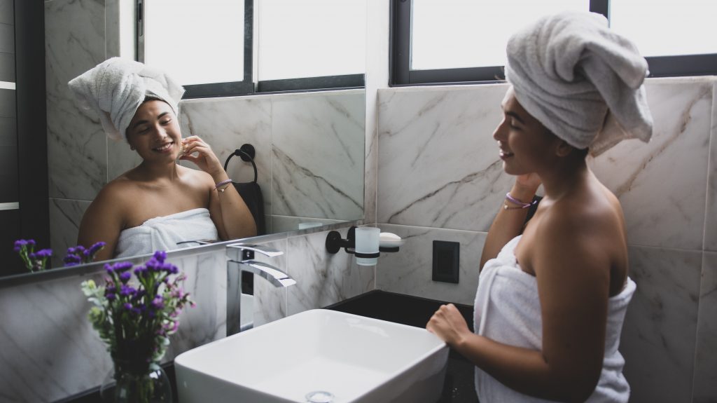 Woman in bathroom taking care of herself by following a self care morning routine