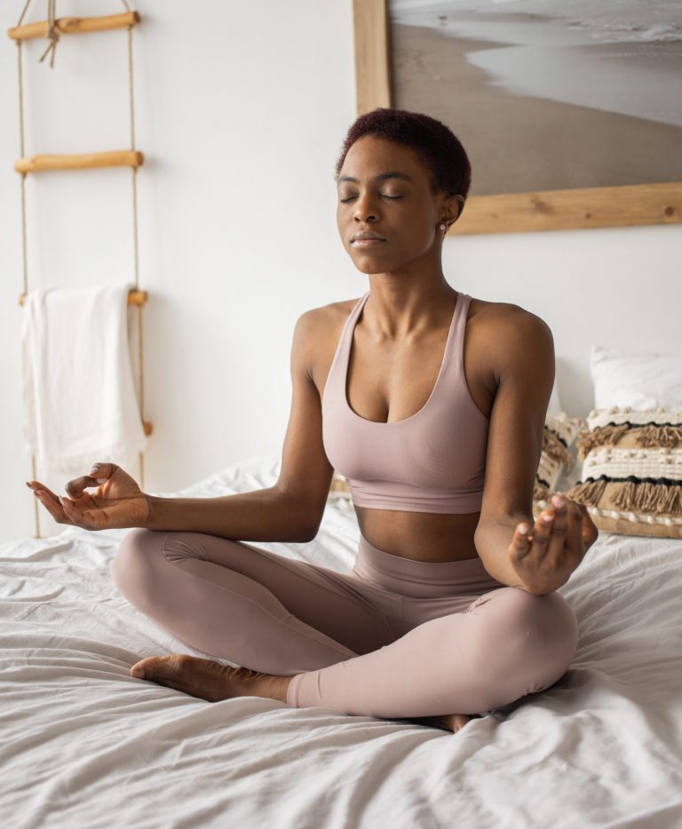 Woman practicing a pose of meditation on bed before sleep