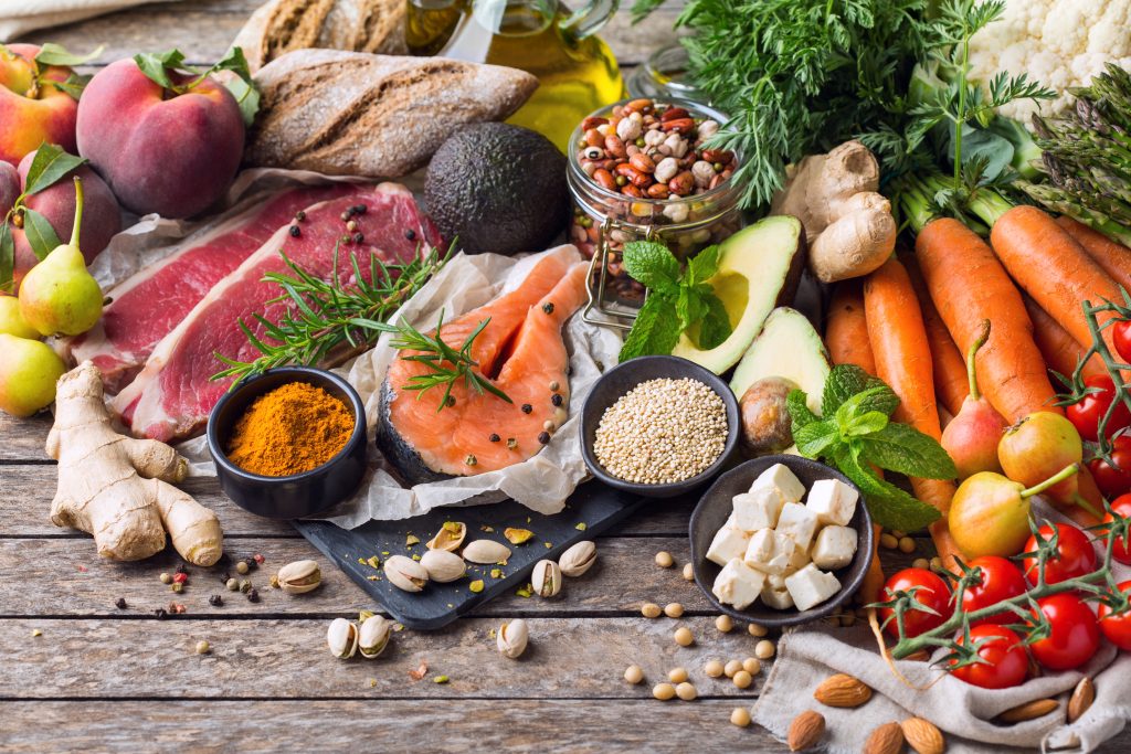 Paleo vs keto diet: paleo foods on the table like vegetables, fruits, salmon, avocado, bread