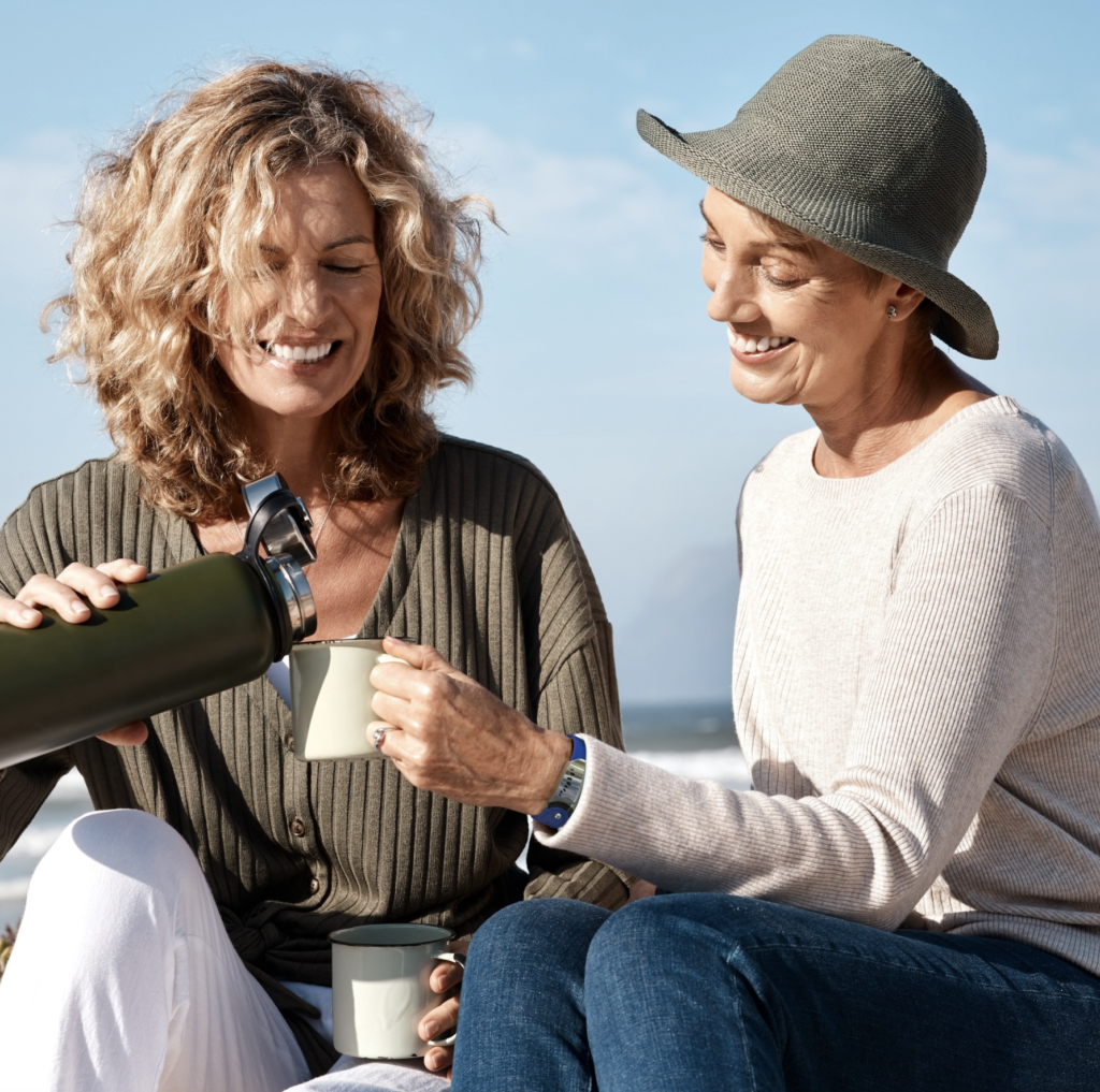 Two woman drinking a cup of tea outside and having a social rest , one of the 7 types of rest.