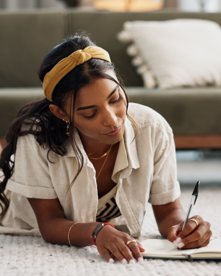 Women practicing journaling before bed and having a gema wellness tracker on her wrist, taking time for one of the 7 types of rest.