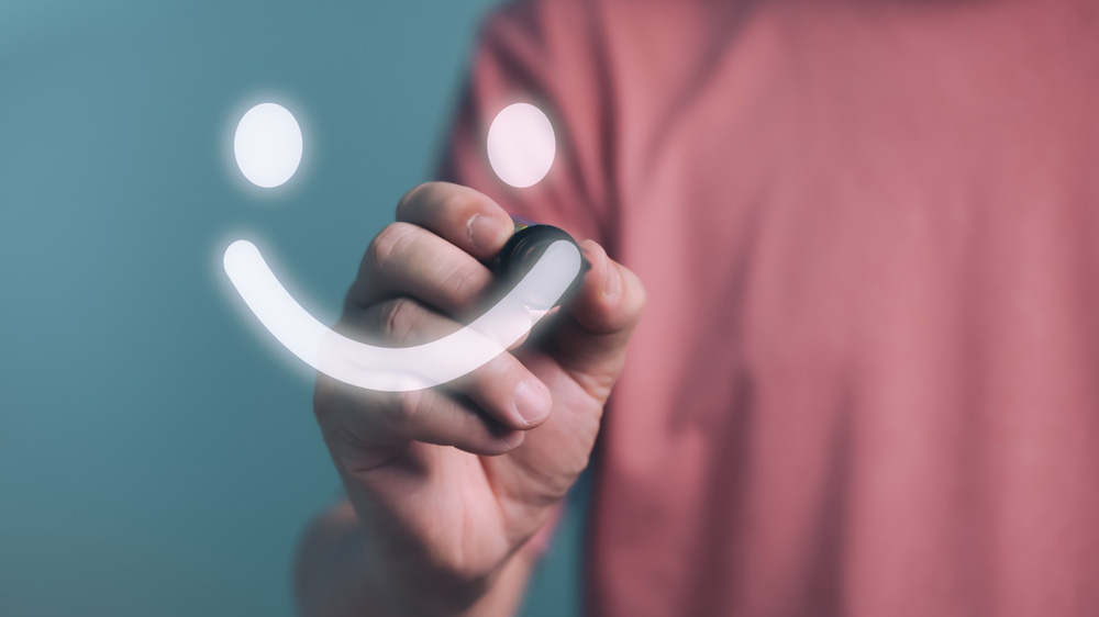 Person drawing a smiley face on a glass