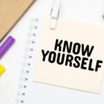 'KNOW YOURSELF ' written on post-it note attached to a Notebook