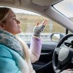 A person is expressing a range of emotions while driving her vehicle
