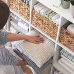 A person putting pilows away in a cupboard