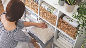 A person putting pilows away in a cupboard