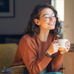 Smiling woman sitting on a couch drinking coffee