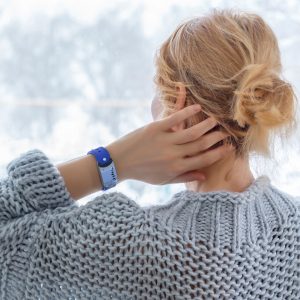 Woman at a windown watching the snow falling with a GEMA Fitness Tracker on her wrist